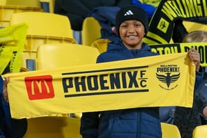 A young fan holding up a McDonalds Wellington Phoenix A-League supporters scarf