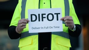 Image of a man in a high-vis vest holding a paper sign