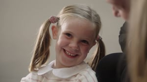 A young girl with pigtails smiling